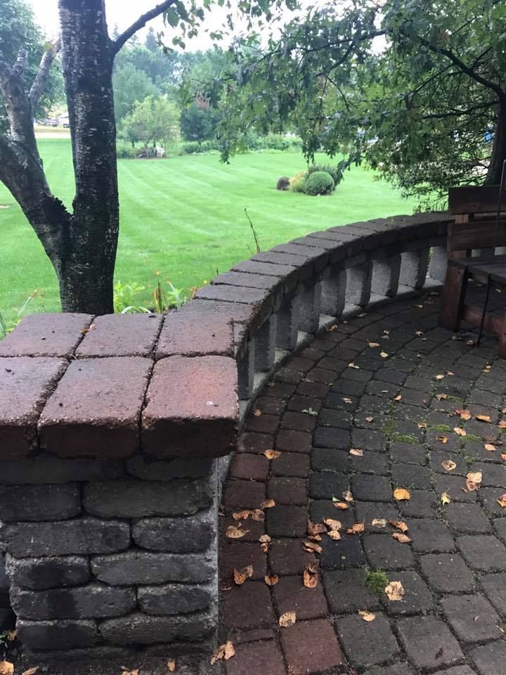 a brick patio with a bench and a tree in the background