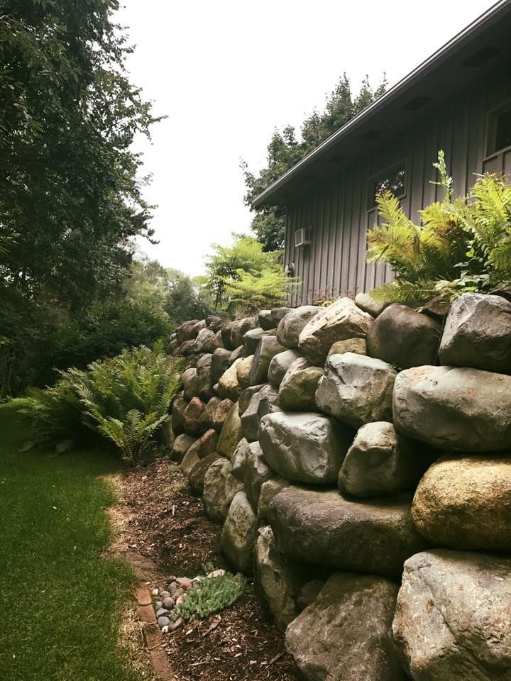 a large rock wall in front of a house
