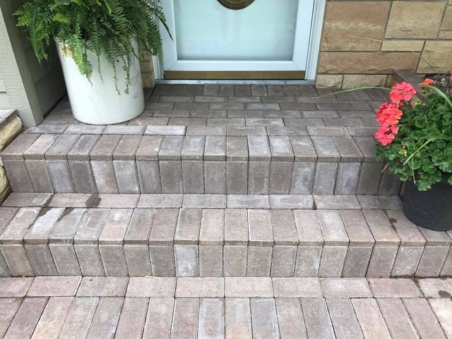 a potted plant is sitting on a brick porch next to a door .