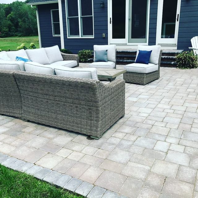 a patio with wicker furniture in front of a blue house