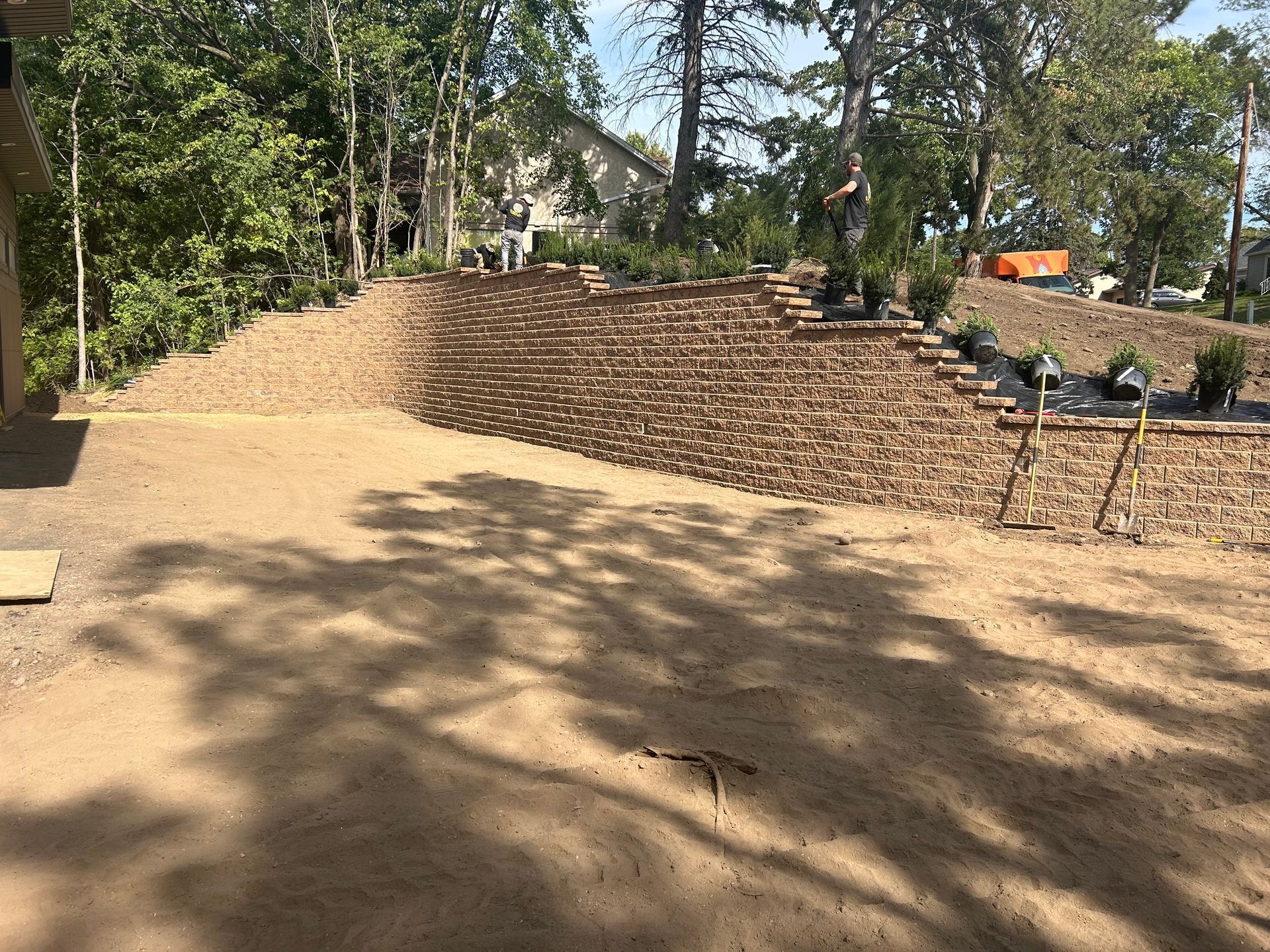 A brick wall is being built in the backyard of a house.