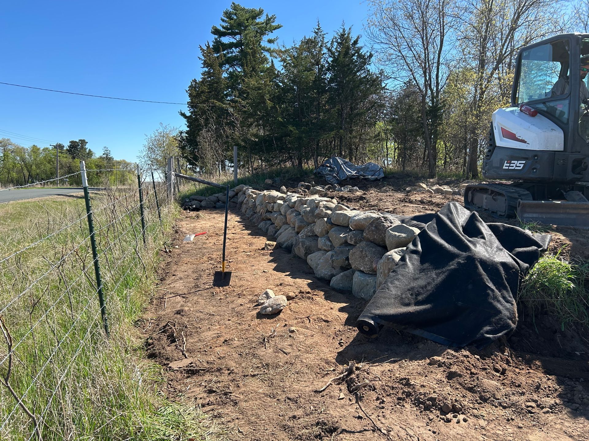 A bulldozer is sitting in the dirt next to a stone wall.