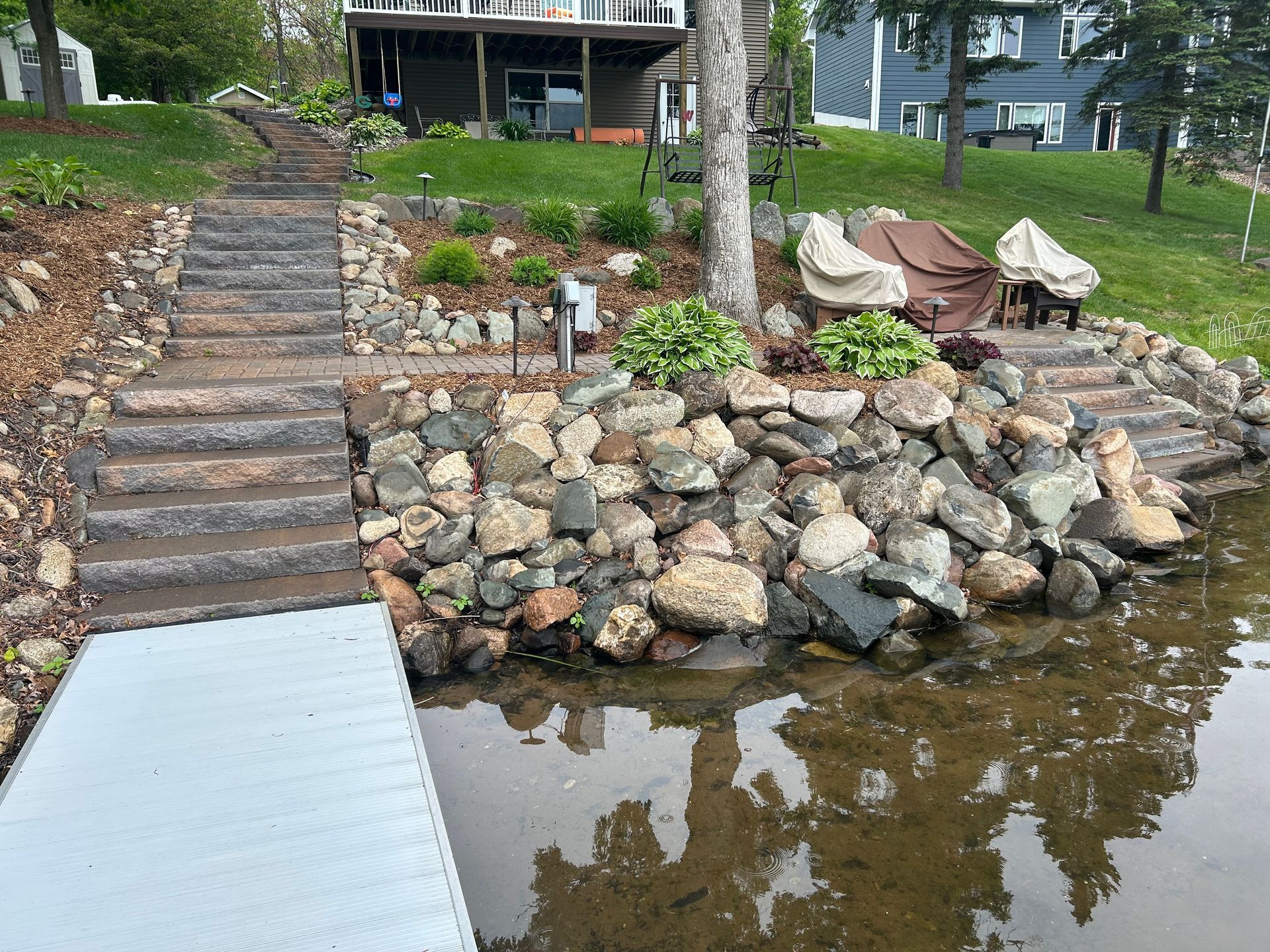A dock with stairs leading to a house next to a body of water.