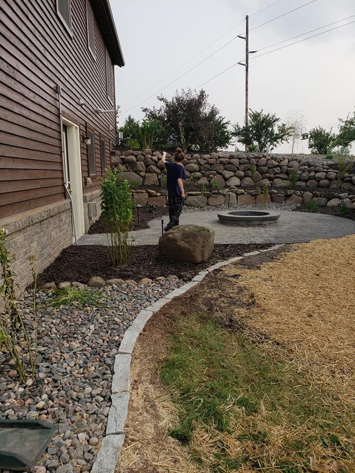 a man is standing in front of a house next to a fire pit .