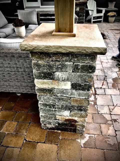 a brick pillar on a patio with a couch in the background