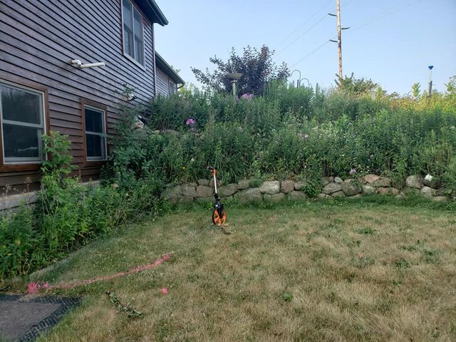 a lawn mower is sitting in the grass in front of a house .