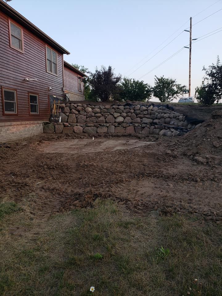 a stone wall is being built in the backyard of a house .