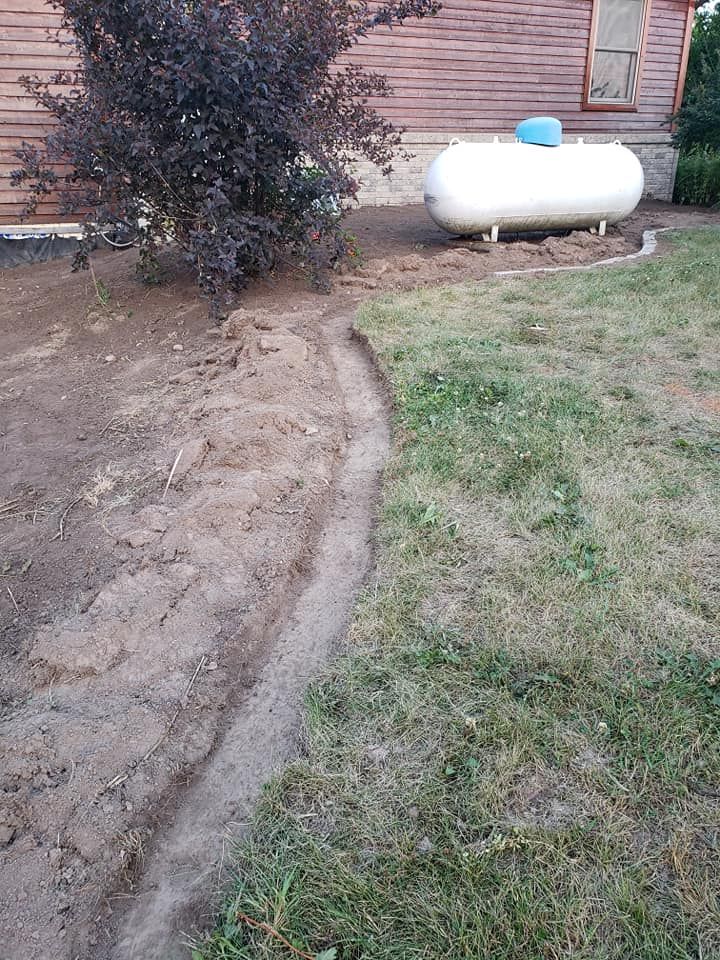 a propane tank is sitting in the grass in front of a house .
