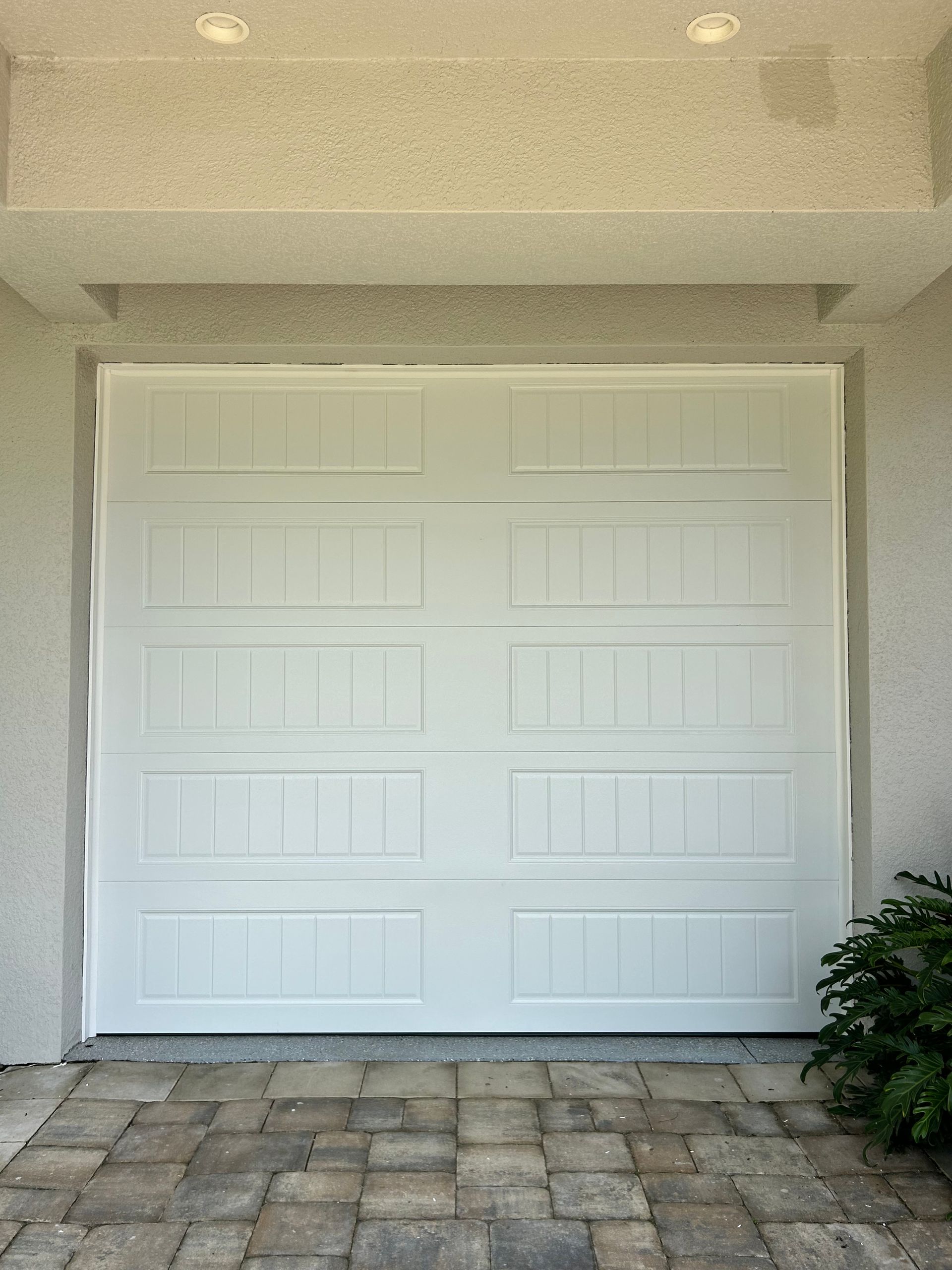 White double garage door with stone paver driveway in a stucco exterior wall