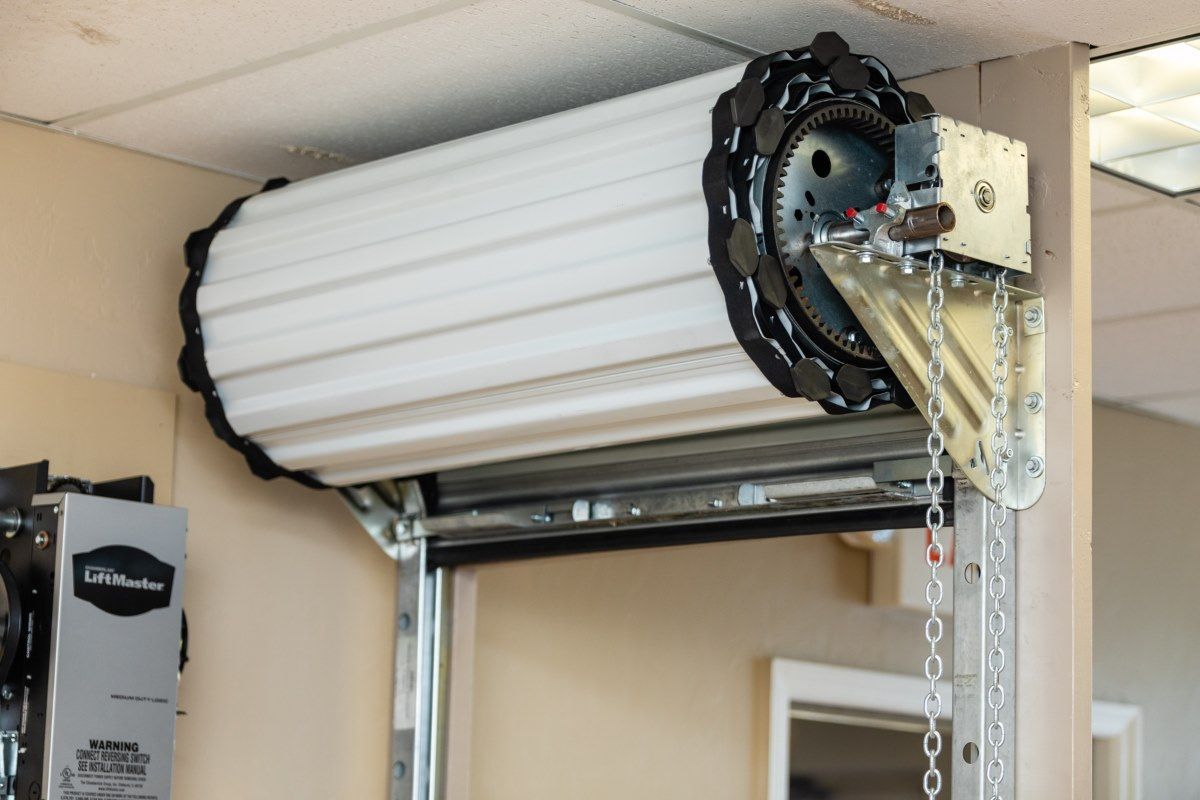 Garage door mechanism with coiled white slats, chain, and metal components.