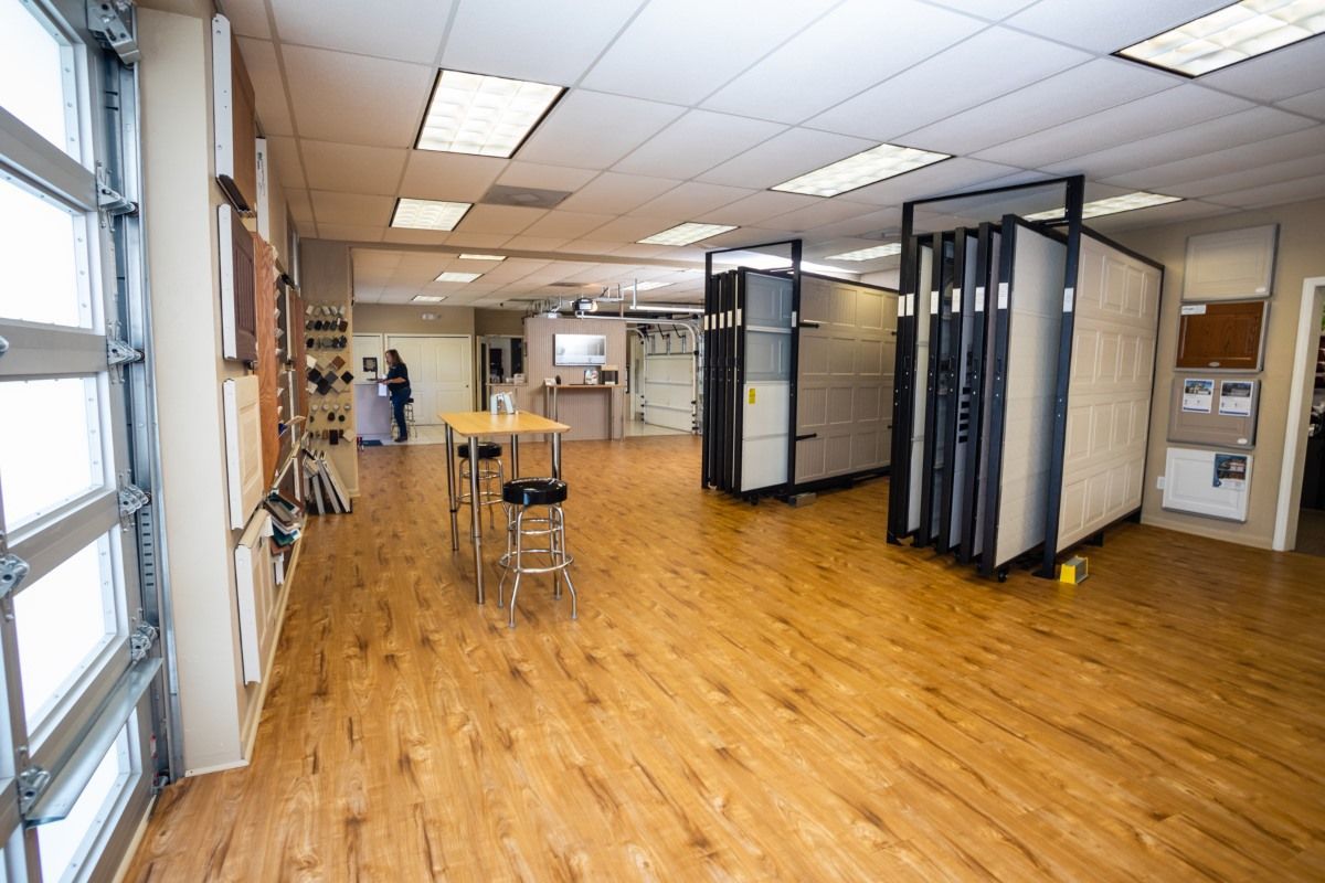 A bright showroom with wood-look flooring, partitions, and samples. Two people are in the background.