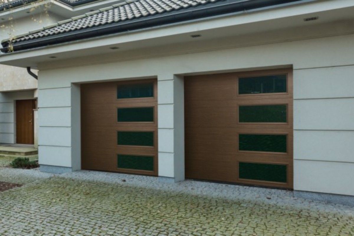 Two brown garage doors with green tinted windows, next to a light-colored house.