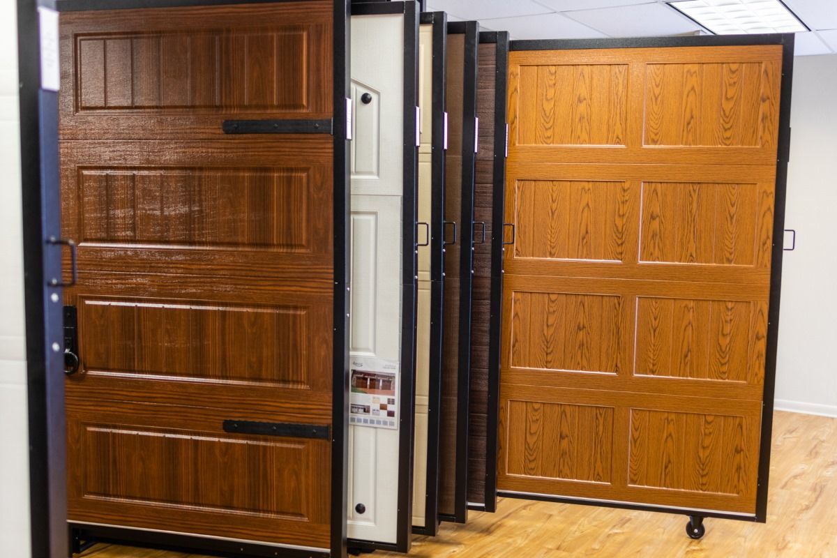 Garage door samples in various wood grain finishes, displayed in a showroom.