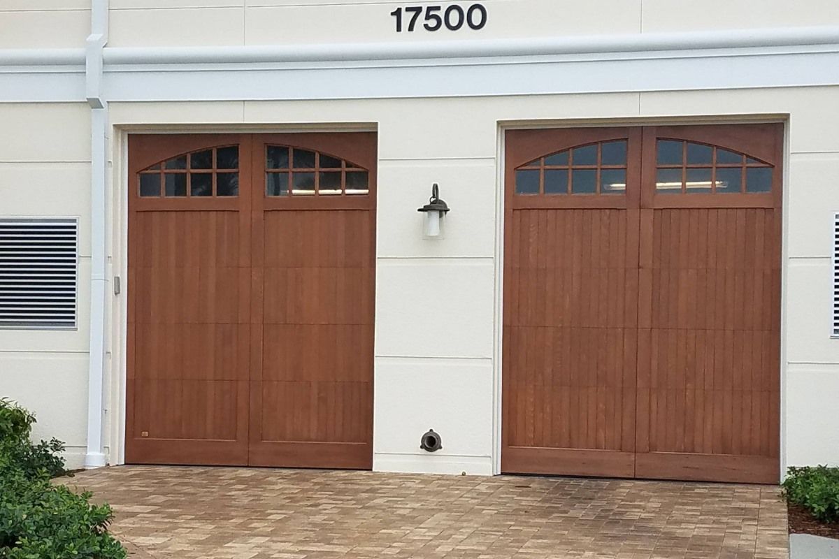 Two brown garage doors with arched glass windows, set in a cream-colored building with the number 17500 above.