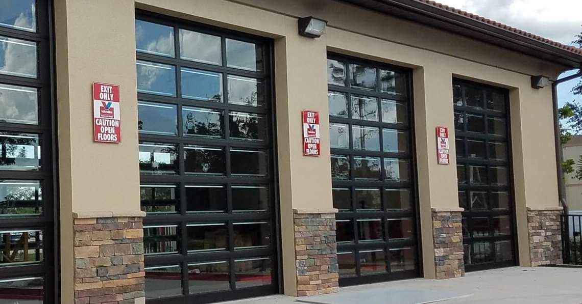 Fire station exterior with glass garage doors, tan walls, and stone accents.