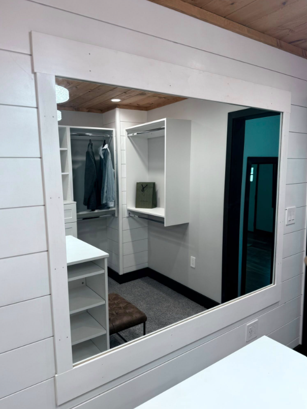 A large mirror is hanging on a wall in a closet.