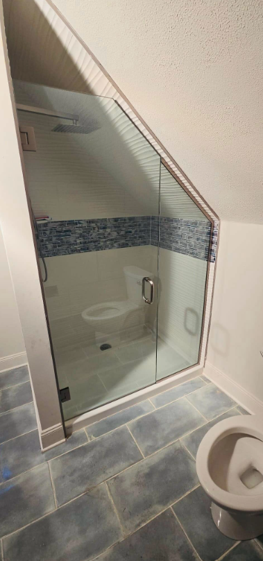A bathroom with a toilet and a shower with a glass door.