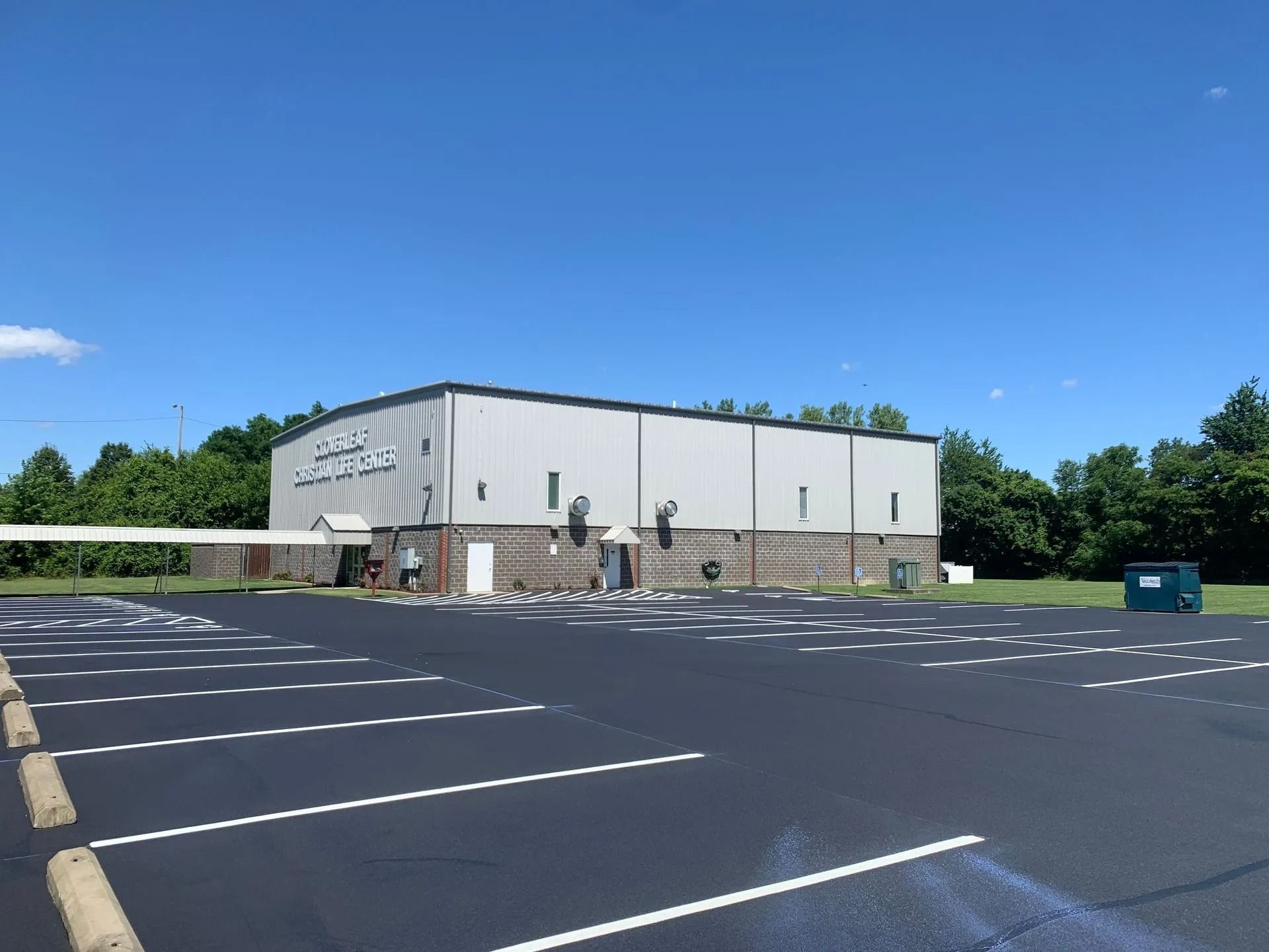 Metal building with a parking lot and blue sky.