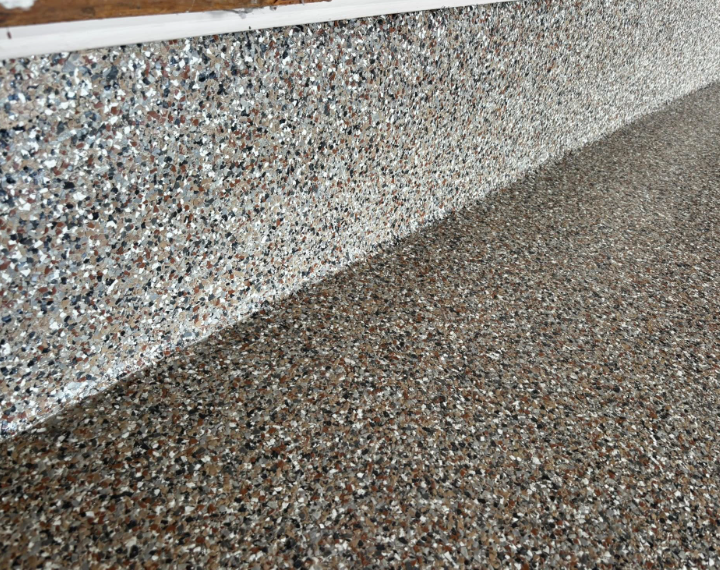 Textured concrete wall and floor, speckled with gray, brown, and white chips.
