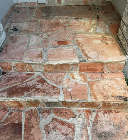 Stone steps leading upwards, reddish-brown color, uneven surface.