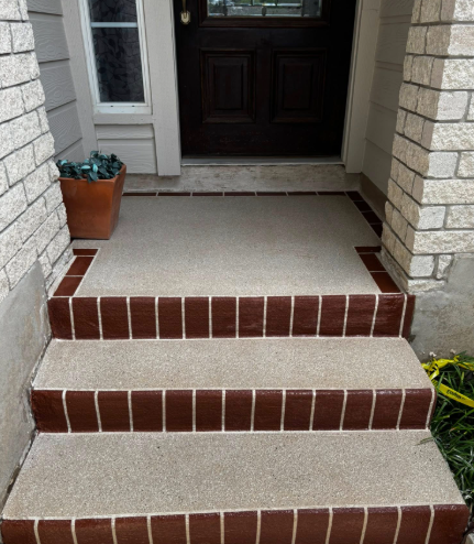 Concrete porch with three brick-edged steps leading to a brown door.