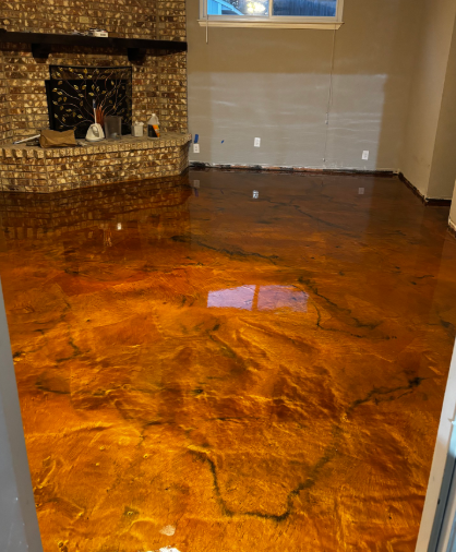 Metallic gold epoxy floor with black veining in a room. Brick fireplace in background.