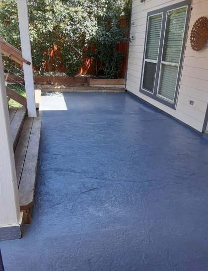 Blue painted concrete patio next to a house with a wooden deck.