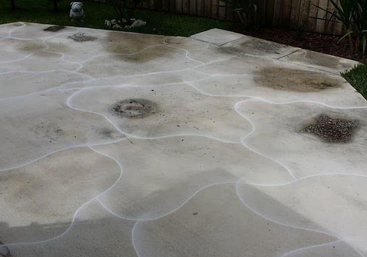 Concrete patio with stained patches and white outlines.