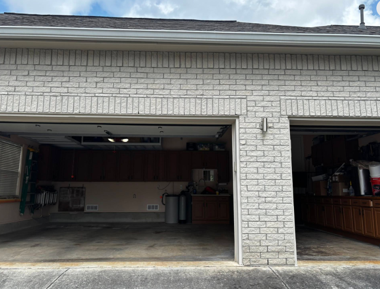 Brick garage with two open bays, gray bricks, and gray concrete floor.