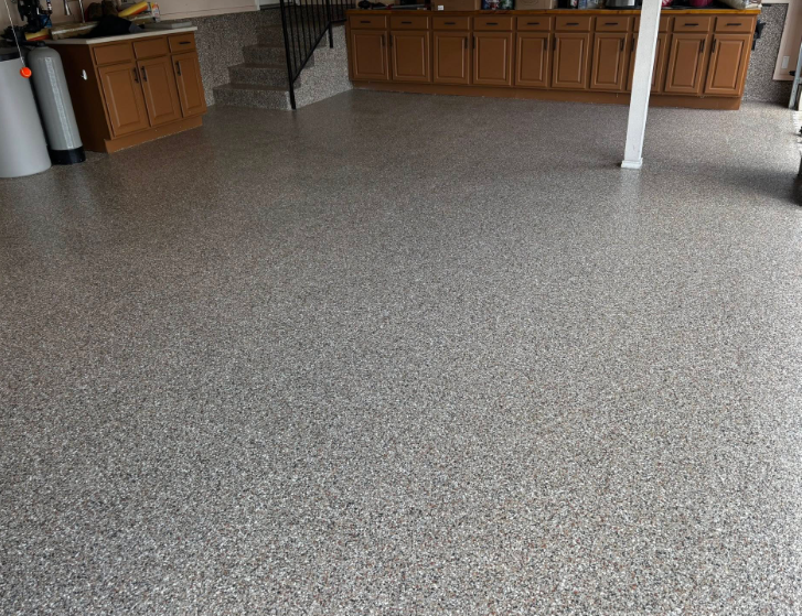 Epoxy-coated garage floor with gray and white flecks; wooden cabinets along the walls.
