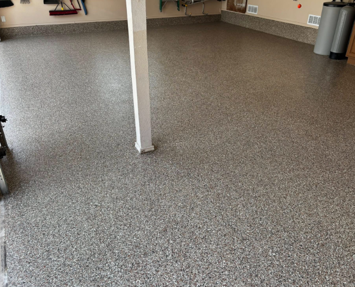 Garage floor with speckled gray epoxy coating, a support beam in the center.
