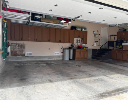 Garage interior with brown cabinets, storage, and concrete floor.