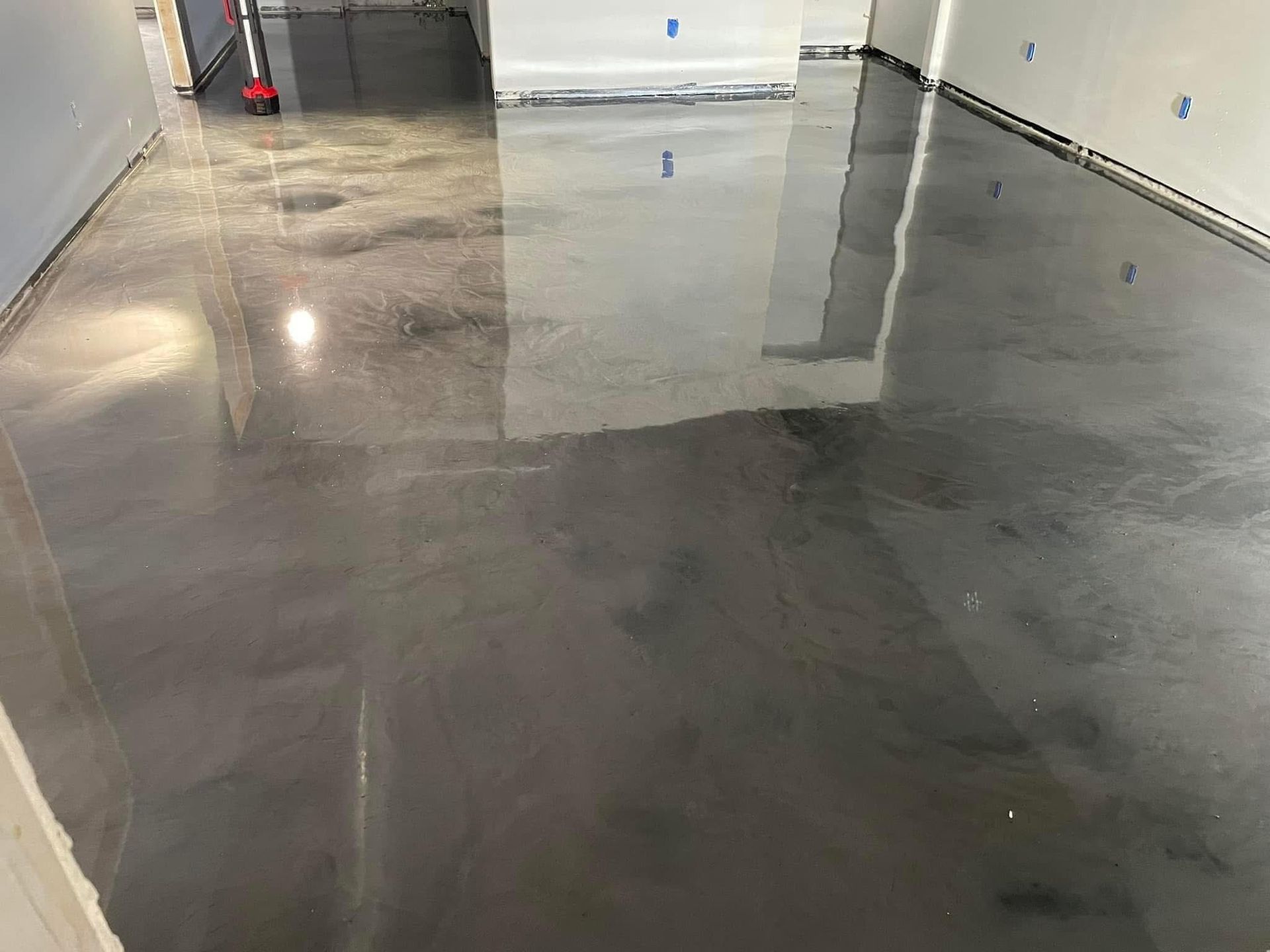 Shiny, metallic gray epoxy floor in an empty room, reflecting light.