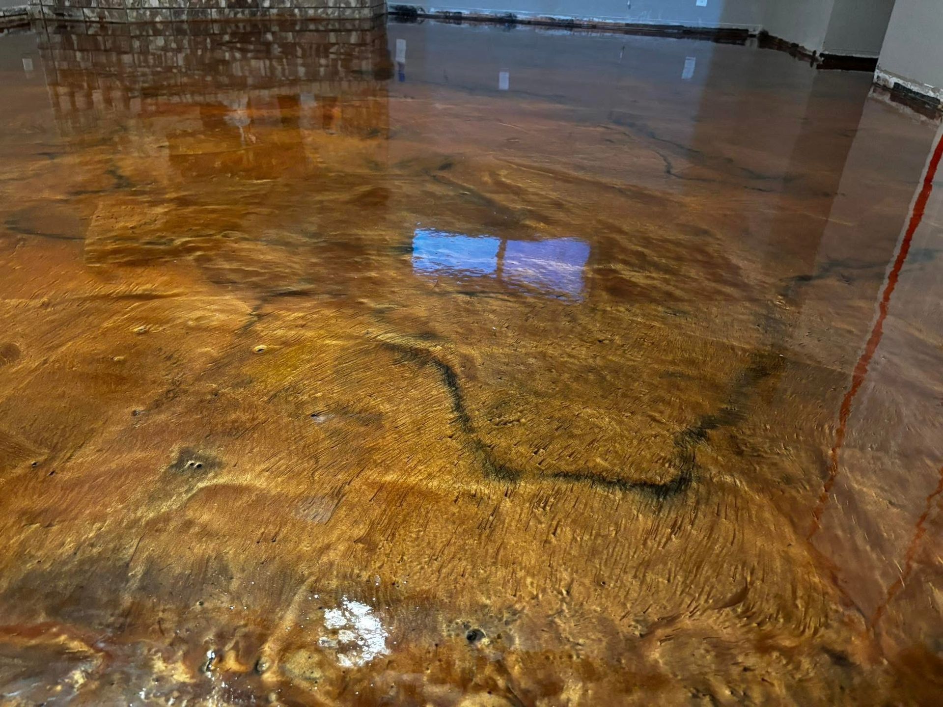Metallic gold epoxy floor, reflecting light. Brown and gold swirls create an abstract pattern.