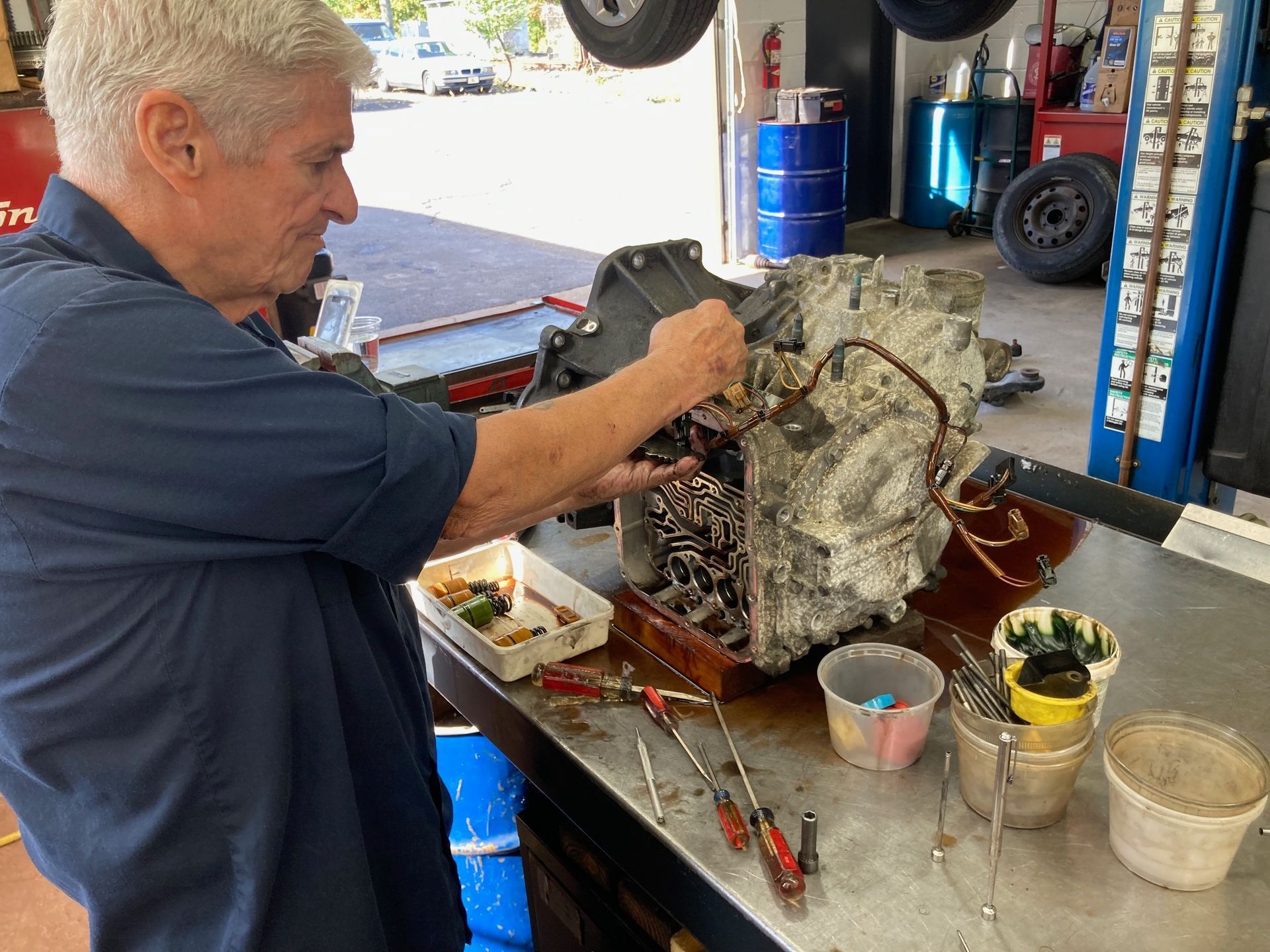 A mechanic working on a car transmission in a repair shop.
