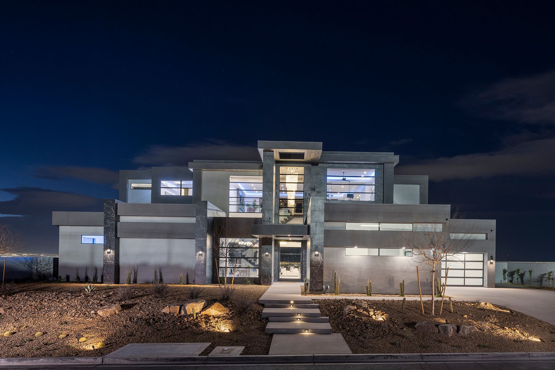 A large modern house is lit up at night.