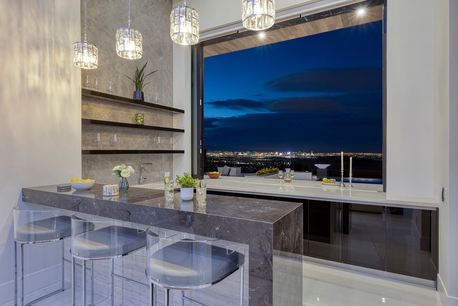 A kitchen with a bar and a large window with a view of the city at night.