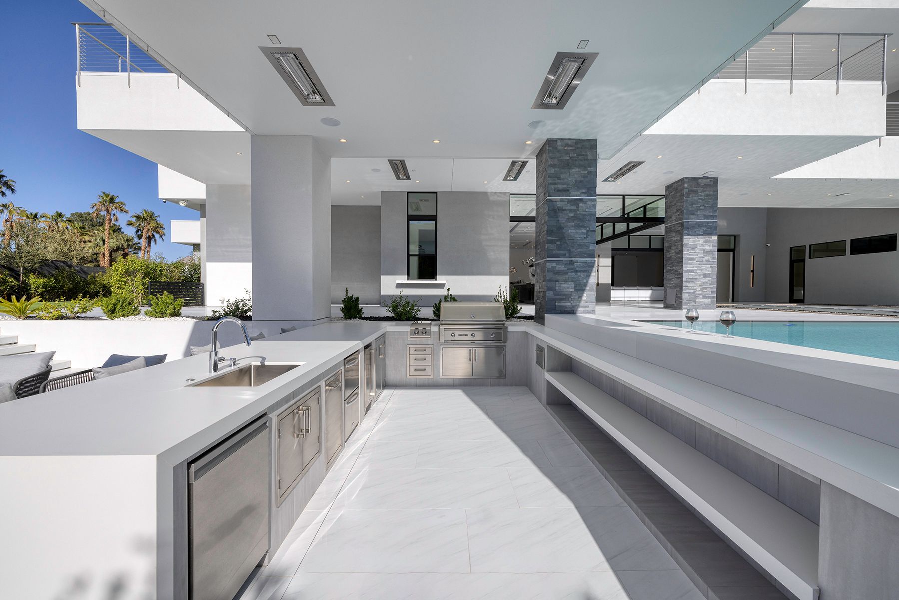 A large kitchen with stainless steel appliances and a swimming pool in the background.