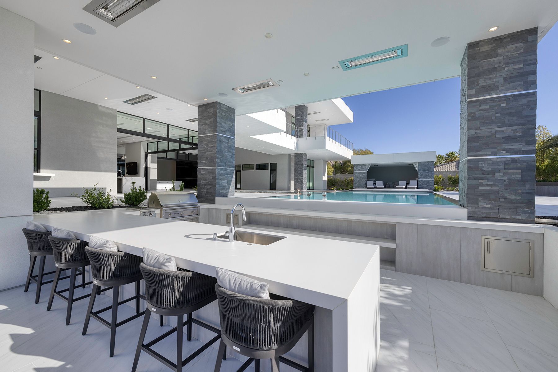 A kitchen with a table and chairs and a swimming pool in the background.