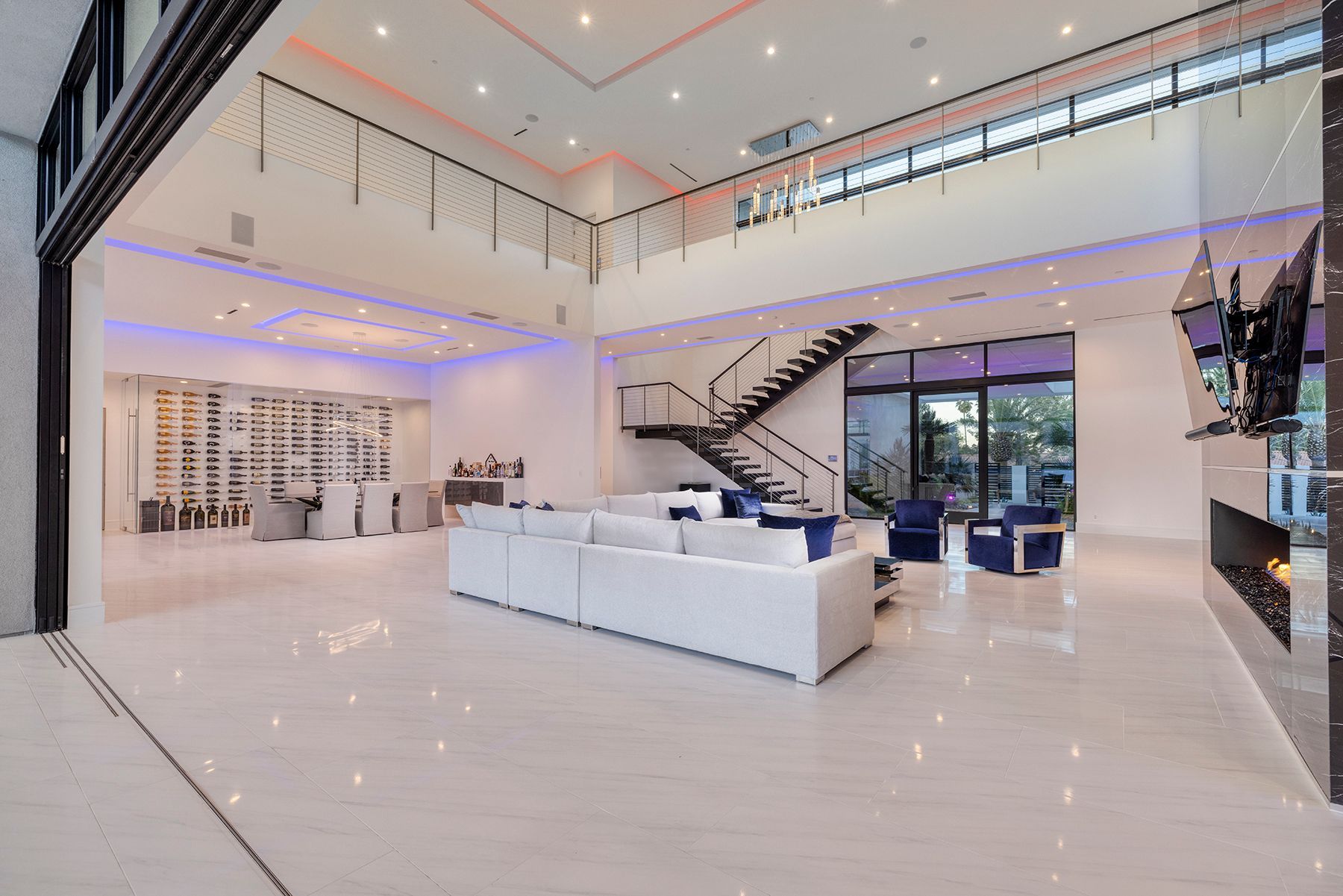 A large living room with a couch, chairs, fireplace, and stairs.
