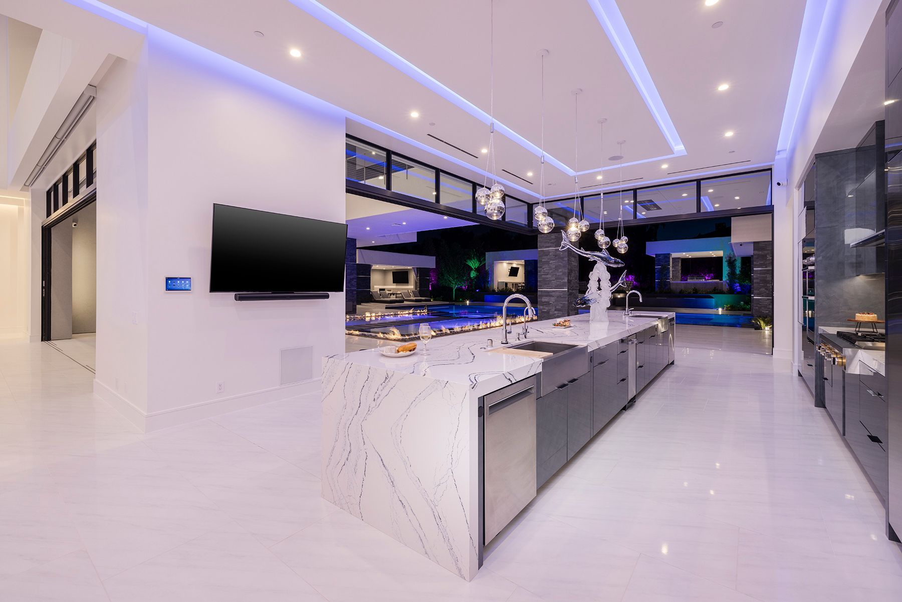 A kitchen with a large island and a flat screen tv on the wall.