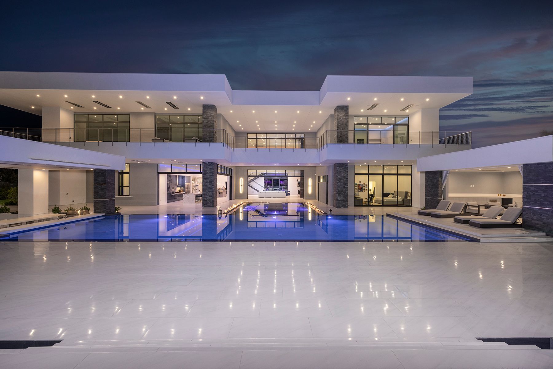 A large white house with a large swimming pool in front of it.