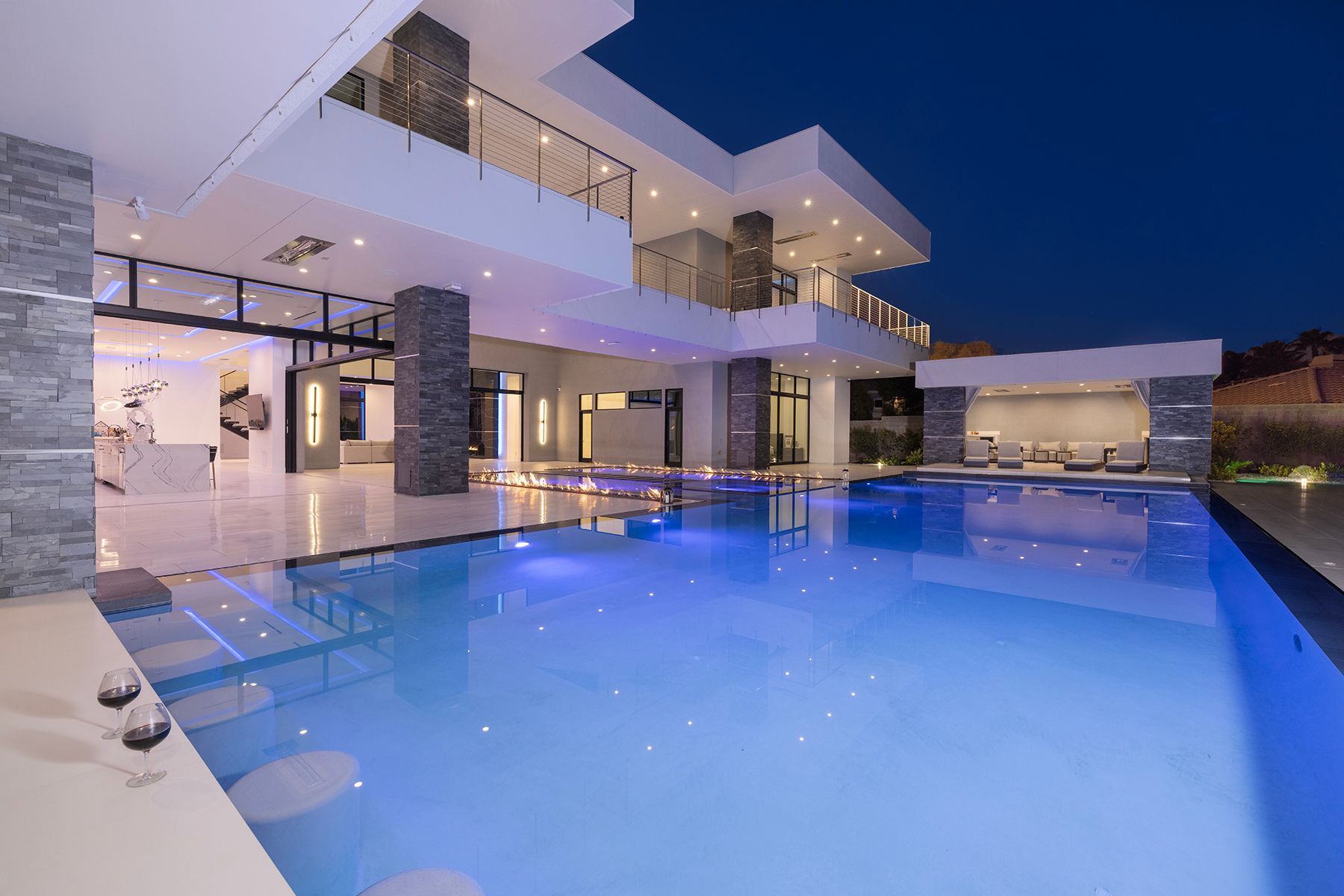 A large house with a swimming pool in front of it at night.