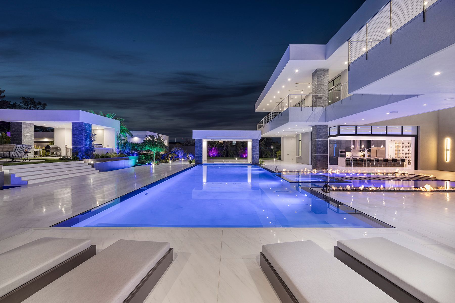 A large swimming pool in the middle of a large house at night.