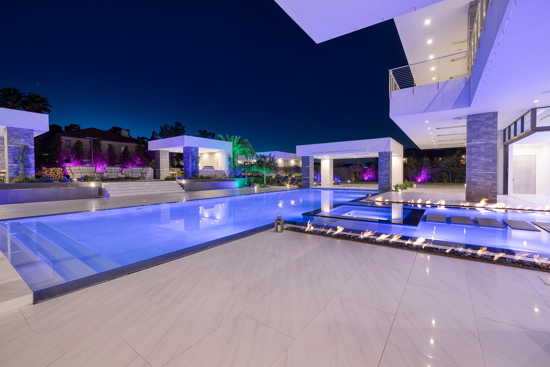 A large swimming pool in the middle of a large house at night.