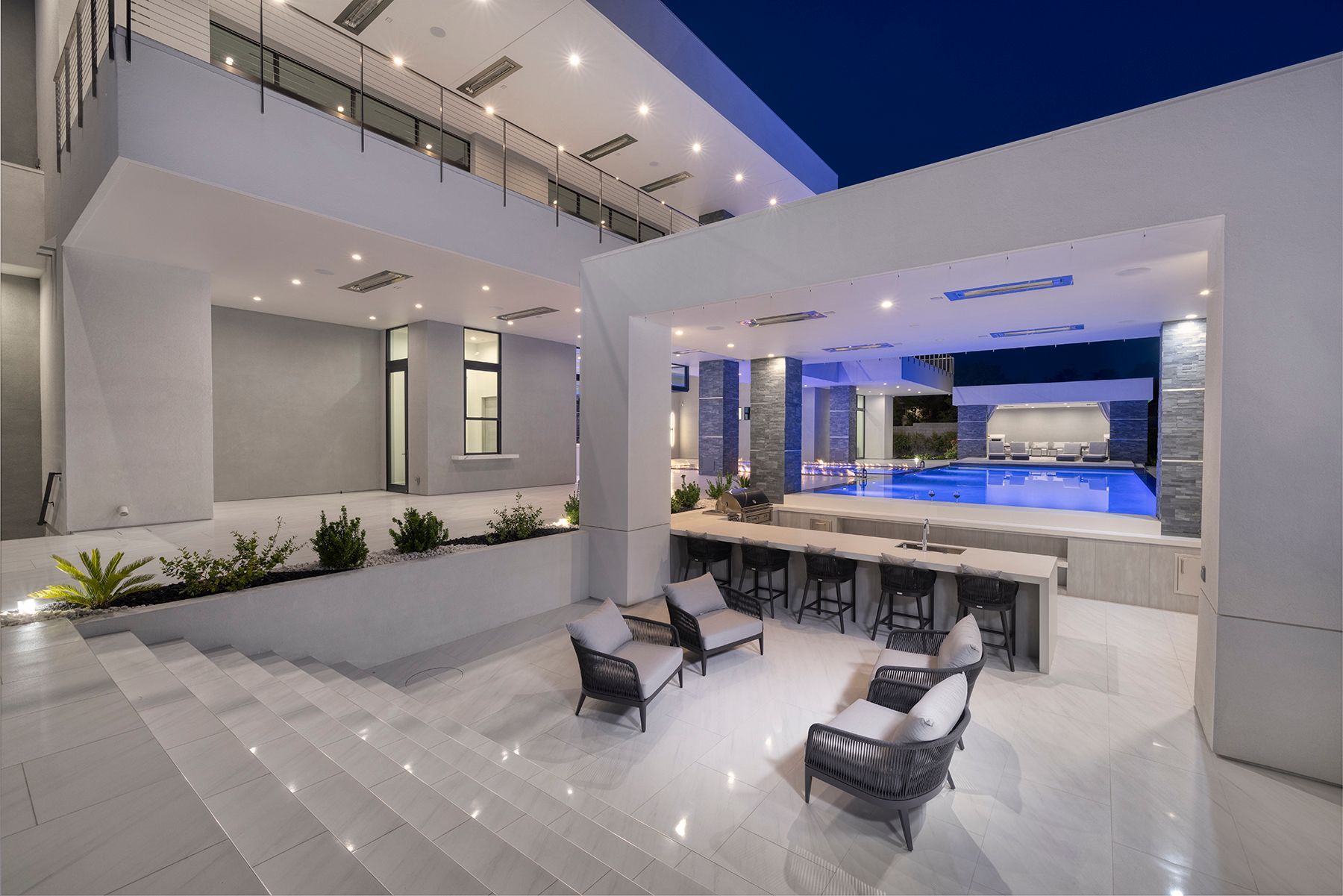 A large house with a swimming pool and a patio area with chairs and tables.