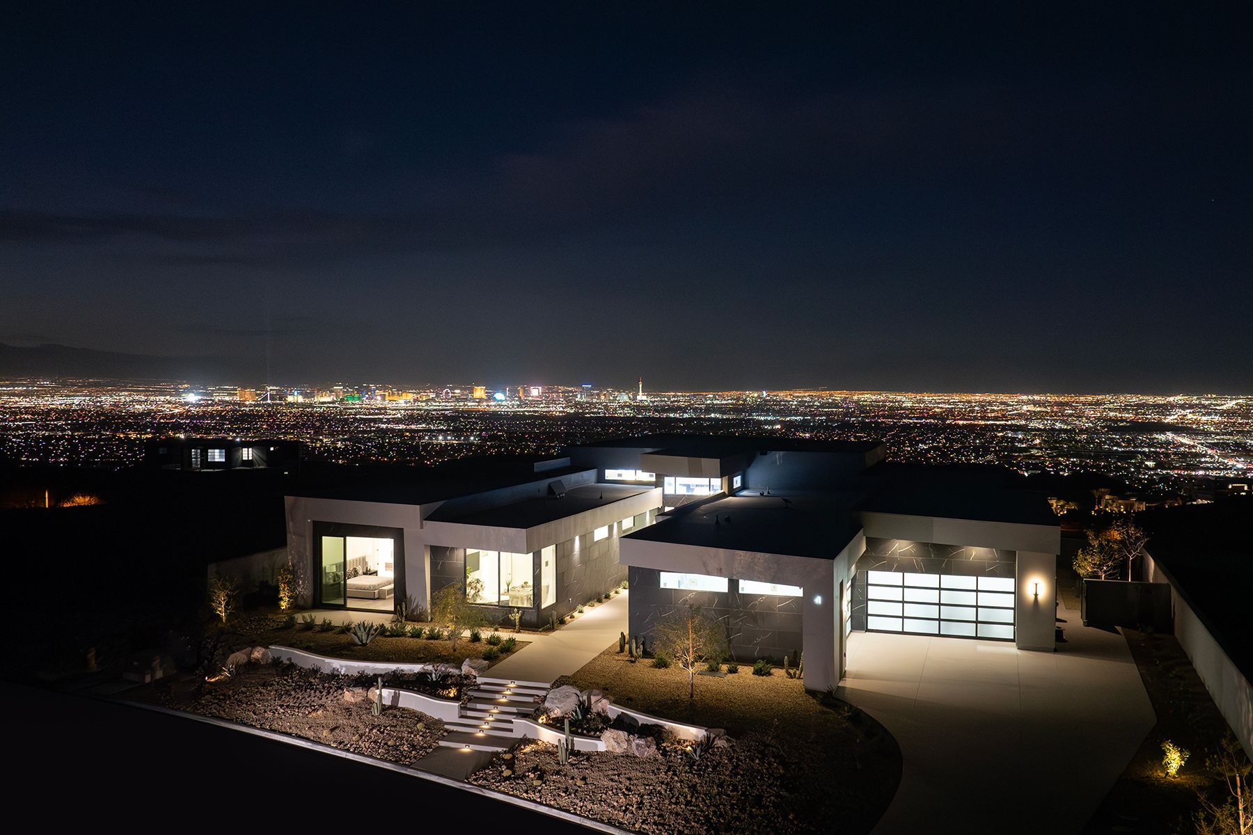 an aerial view of a house at night with a city in the background