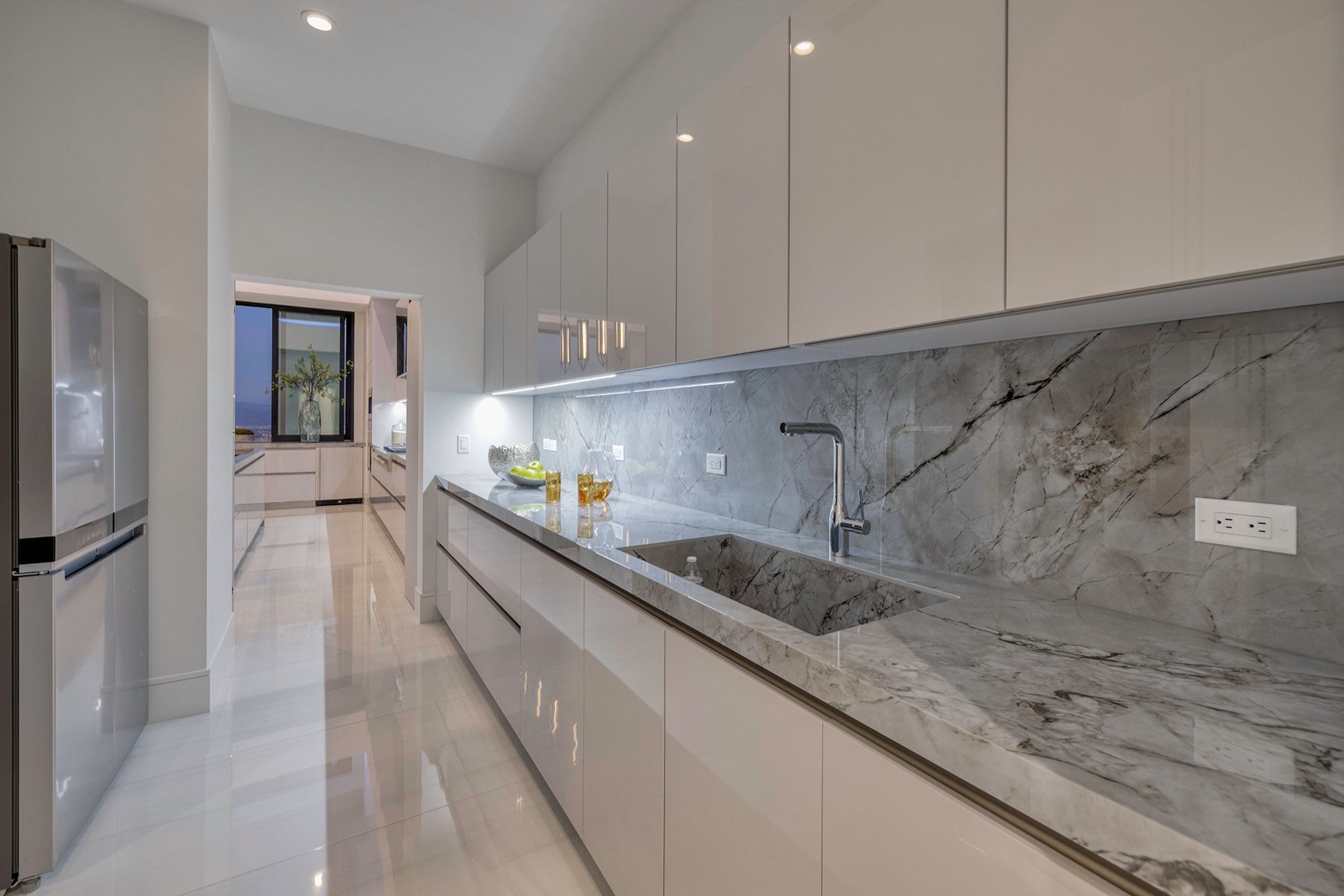 a kitchen with white cabinets and marble counter tops