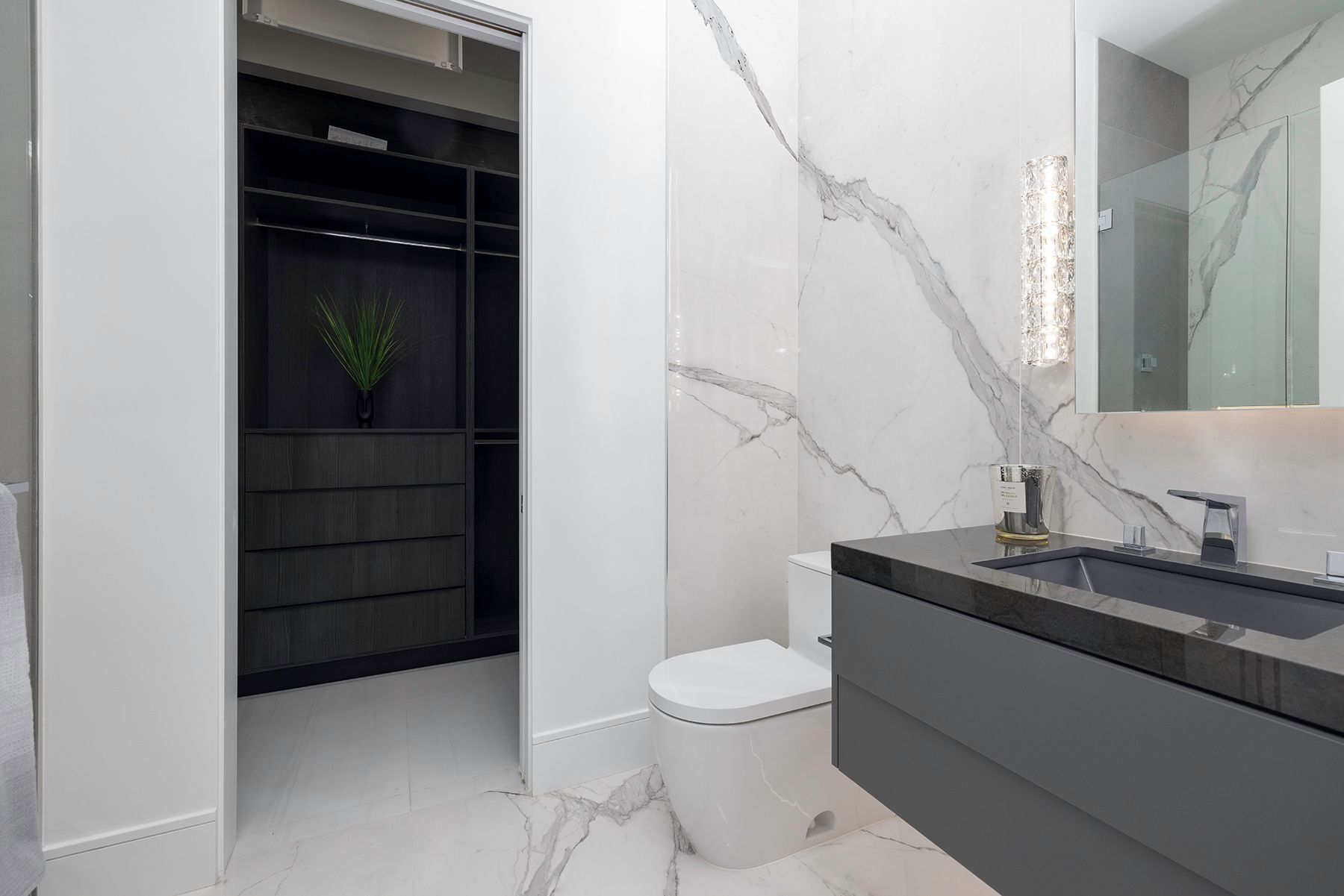 a bathroom with a toilet, sink and walk-in closet