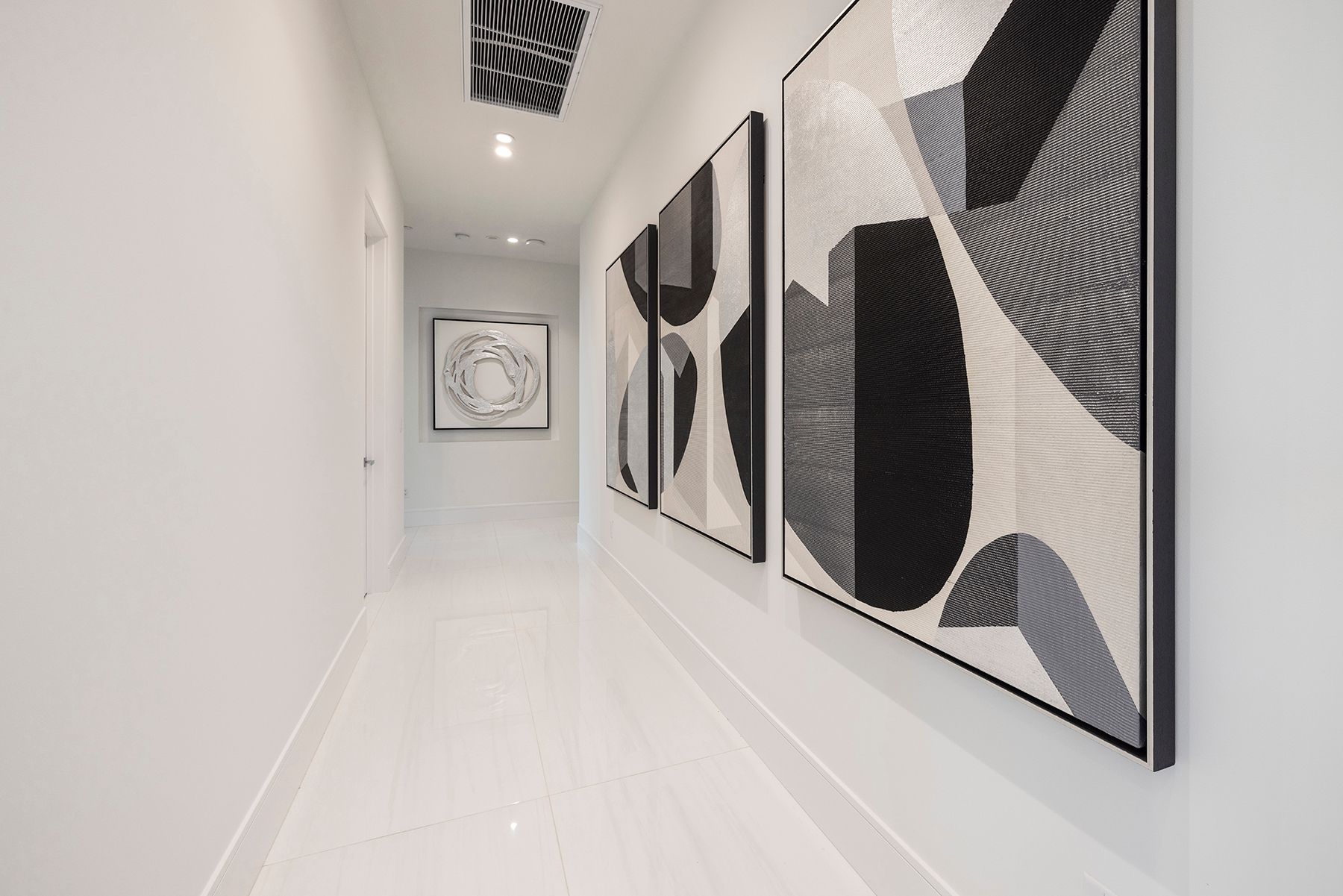 a hallway with black and white paintings on the wall